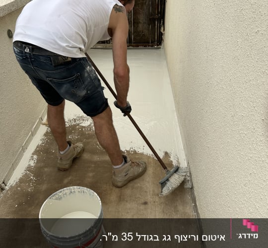 אדם צובע רצפה בצבע לבן עם מברשת